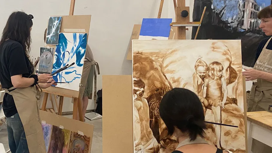 Artists painting on canvases in a studio.