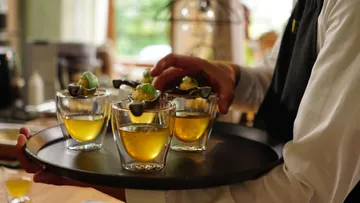Waiter serves drinks with appetizers indoors.