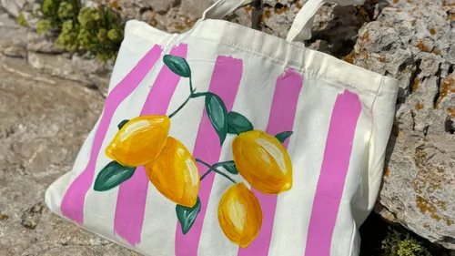 Stofftasche mit Zitronen auf Felsen.