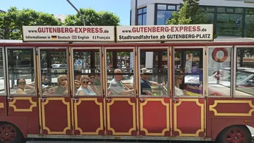 Tourist tram with passengers, city street.