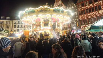 Carousel spinning, crowded Christmas market at night.