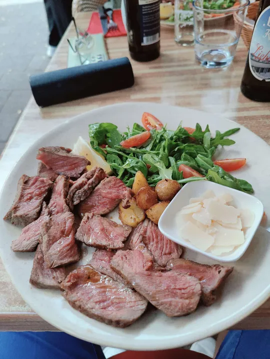 Teller mit Steak, Salat und Kartoffeln auf Tisch.