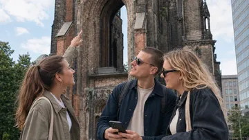 Three people look at tall church ruin.