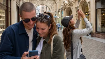 Couple smiling, looking at smartphone in gallery.