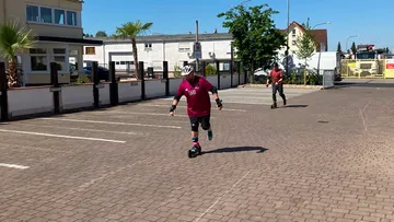Two people rollerblading in a parking lot.