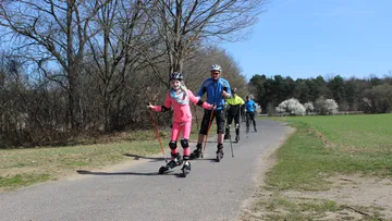 People roller skiing on a country path.