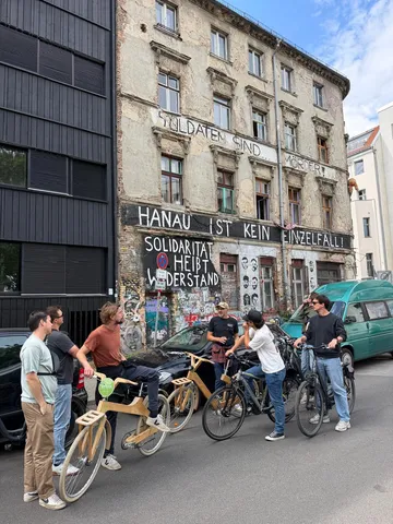 Gruppe mit Fahrrädern vor Graffiti-Gebäude.