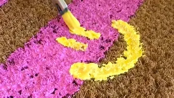 Pinsel malt gelbes Smiley auf Fußmatte
