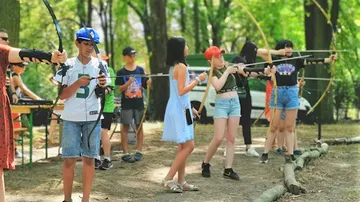 People practicing archery in a forest setting.
