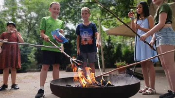 Children roasting marshmallows over campfire outdoors.
