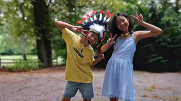 Children posing with peace signs in a park.