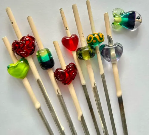 Colorful glass beads on metal sticks, white background.