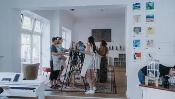 Personen malen an Staffeleien im Atelier.