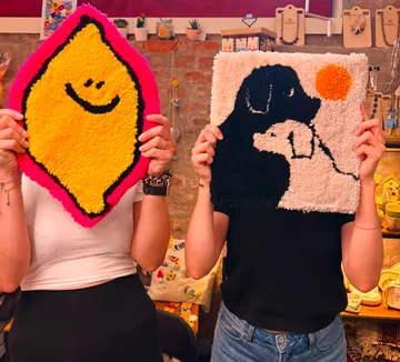 Zwei Personen halten farbenfrohe Textilkunst.