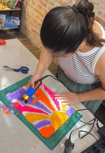 Woman using tool on colorful fabric art.