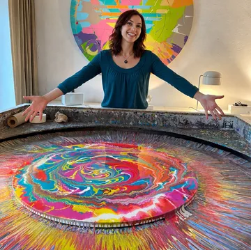 Frau präsentiert bunte, rotierende Kunst drinnen.