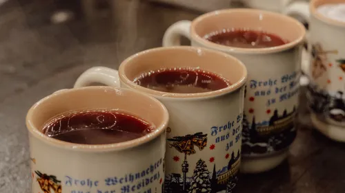 Tassen mit heißem Wein auf Holztisch.