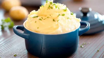 Mashed potatoes served in blue pot on table.