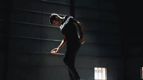 Man balancing in dark industrial space.