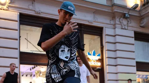 Man wearing graphic shirt walking outdoors.