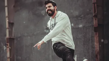Man smiling, wearing hoodie, urban background.