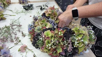 Person arranging flowers on a table.