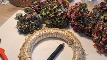 Wreath base with dried hydrangeas on table.