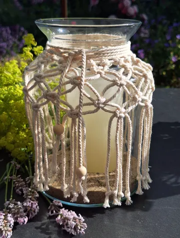 Glass jar with macramé cover, in garden.