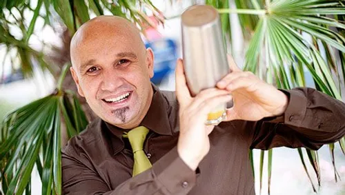Bartender shaking cocktail shaker outdoors.