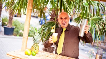 Man making cocktail under palm tree.
