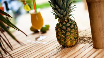 Pineapple on bamboo with tropical drink.