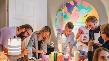 Menschen basteln mit Papier an einem Tisch drinnen.