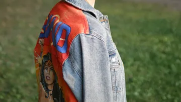 Denim jacket with painted superhero, outdoors.