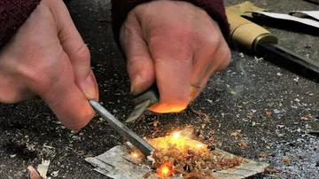 Hände entzünden Feuer mit Zunder im Freien.