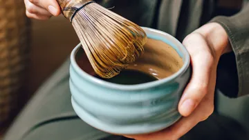 Matcha-Besen rührt in Keramikschale.