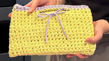 Crocheted pouch held by person's hands.