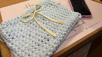 Crocheted pouch with bow on desk.