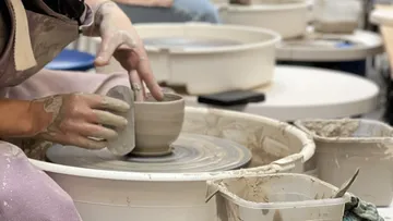 Potter shaping clay on spinning wheel in studio.