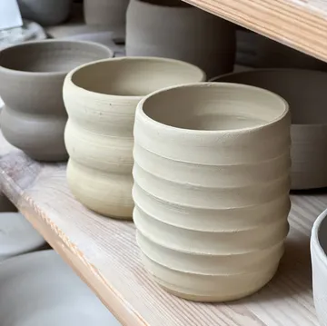 Clay pots drying on wooden shelves.