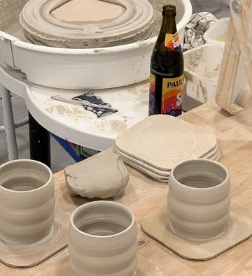 Ceramic cups on pottery wheel in workshop.