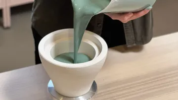 Liquid poured into ceramic pot on table.