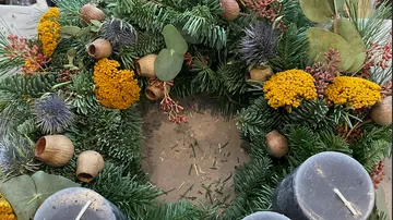 Decorative wreath with candles and flowers.