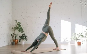 Person macht Yoga-Posen auf Matte drinnen.