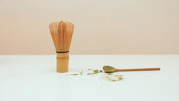 Matcha-Besen neben grünem Teepulver.