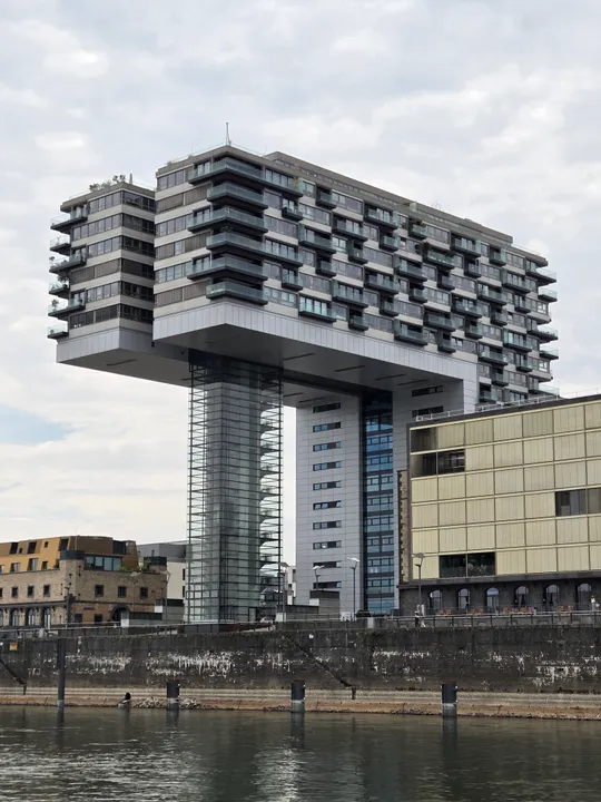 Modern building cantilevers over a river.