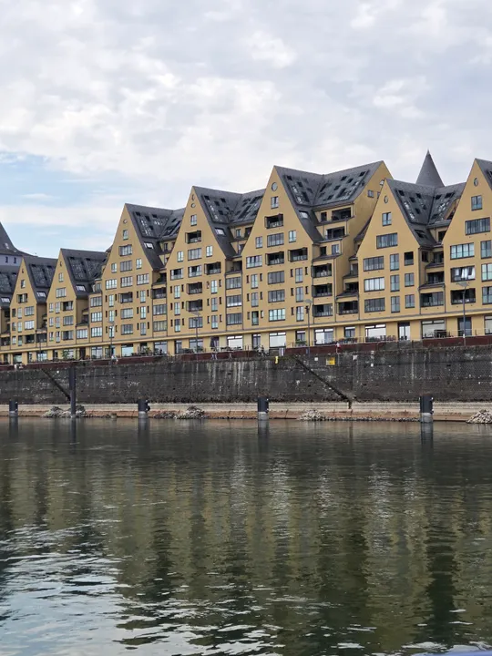 Modern buildings with pointed roofs by a river.
