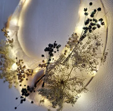 Dried flowers on illuminated wreath, wall background.