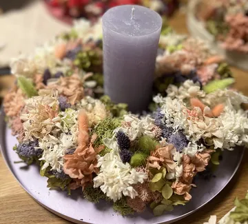 Lila Kerze von Trockenblumen umgeben.