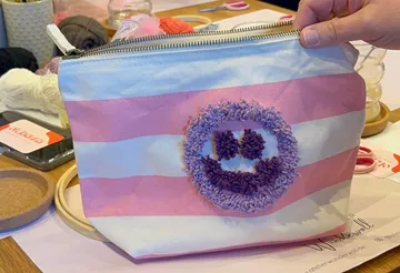 Gestreiftes Etui mit Smiley-Design in Hand.