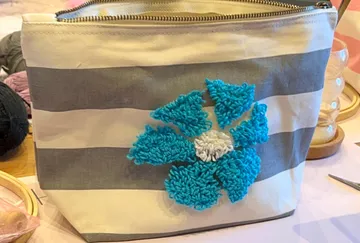 Gestreifte Tasche mit gehäkelter blauer Blume.